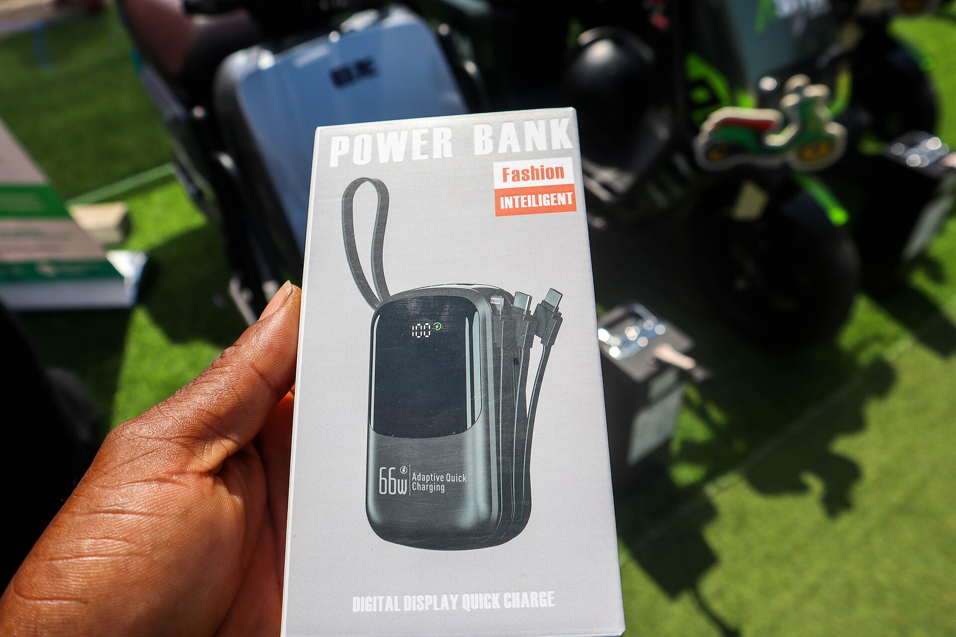 A boxed 66 W power bank with built-in cables held up in a hand